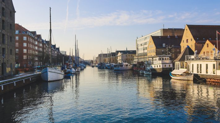 Wide shot of boats on the body of water near buildings in christianshavn, copenhagen, denmark - Scandinavian languages