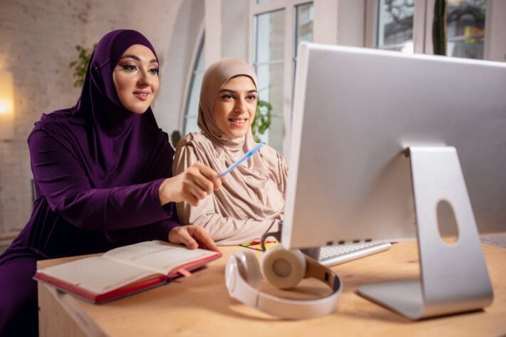 Two women studying Arabic pronunciation on their computer