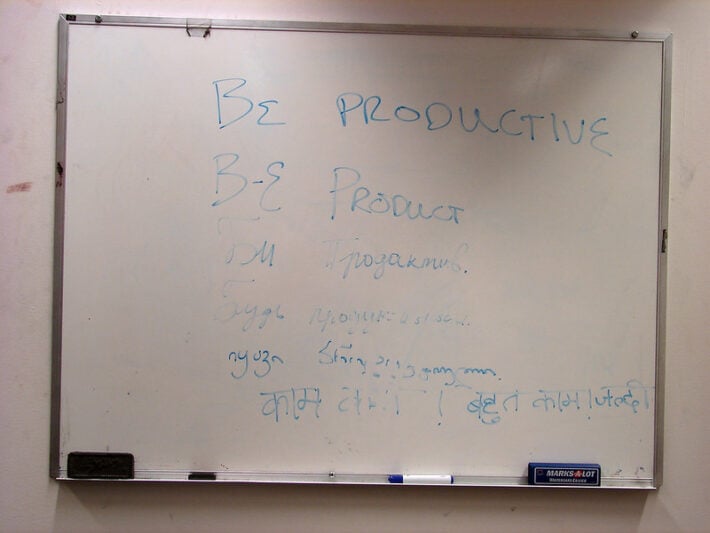 Whiteboard with the phrase "Be productive" in 6 languages, including Hindi