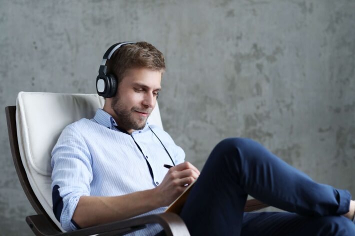 Handsome blond man learning Tamil with songs and taking down notes