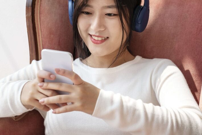 Young asian woman listening to Korean podcasts on her phone