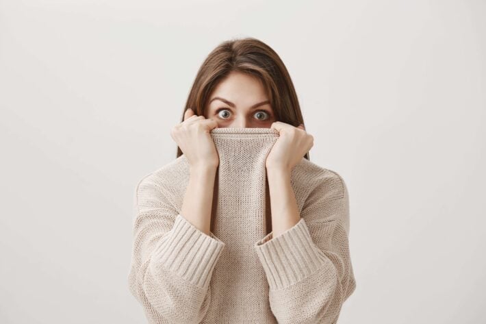 Woman hiding her face inside her sweater because she's afraid of learning Japanese.