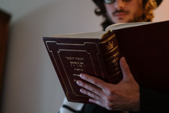 Close-up of a person reading from a Hebrew Torah scroll.